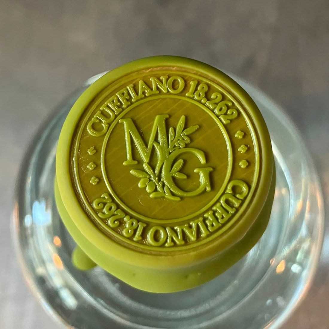 Il tappo visto dall'alto: il sigillo in ceralacca verde oliva con il monogramma MG intrecciato a un ramo d'ulivo, circondato dalla scritta Cuffiano 18.262.